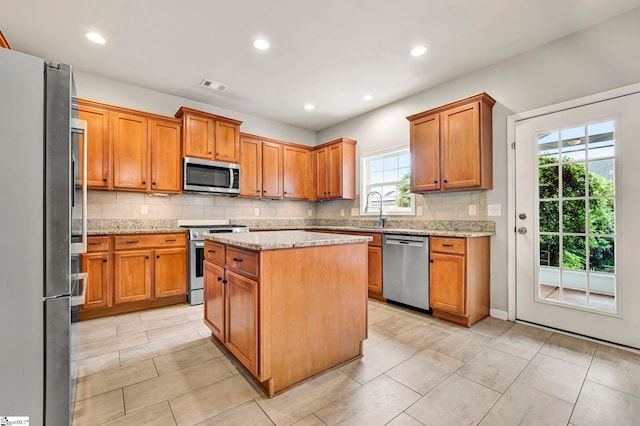 kitchen with brown cabinetry, visible vents, stainless steel appliances, and tasteful backsplash