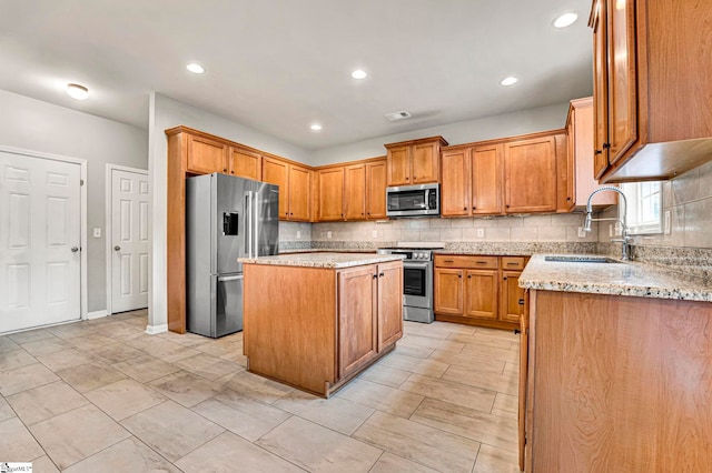 kitchen with appliances with stainless steel finishes, light stone countertops, decorative backsplash, and a sink