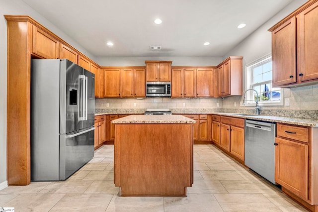 kitchen with decorative backsplash, stainless steel appliances, a kitchen island, a sink, and visible vents