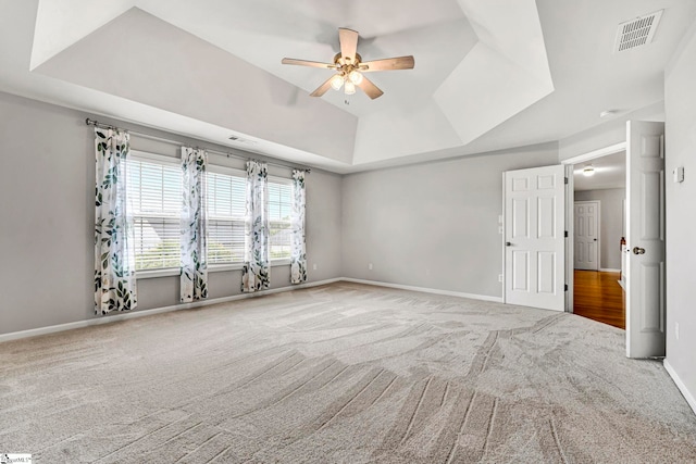 carpeted spare room with visible vents, ceiling fan, a raised ceiling, and baseboards