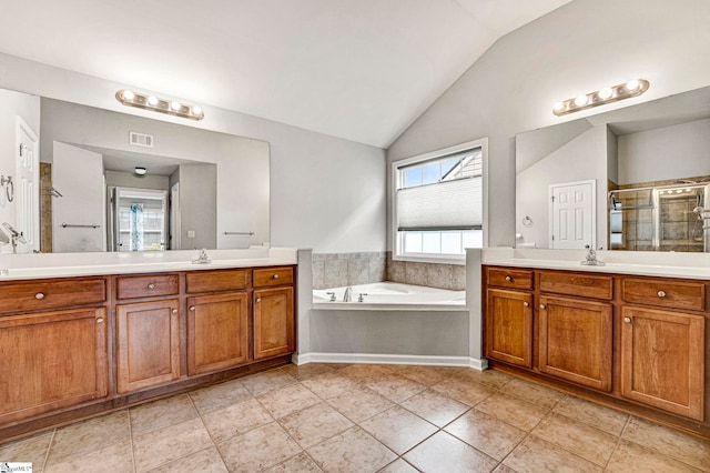 bathroom with a shower stall, visible vents, two vanities, vaulted ceiling, and a garden tub