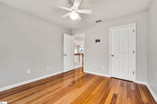 unfurnished bedroom with wood finished floors, visible vents, a ceiling fan, and baseboards