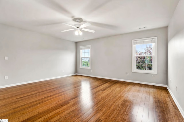 unfurnished room with visible vents, ceiling fan, baseboards, and wood-type flooring