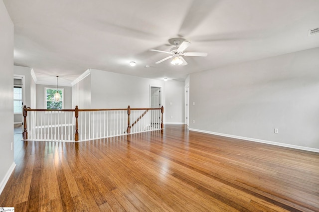 empty room featuring baseboards, visible vents, wood finished floors, and ceiling fan