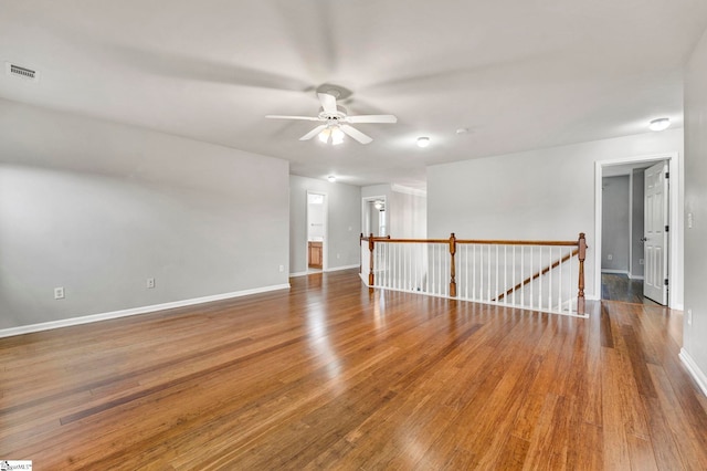 spare room with baseboards, visible vents, wood finished floors, and ceiling fan
