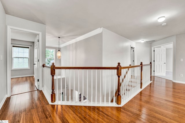 corridor with baseboards, wood finished floors, and an upstairs landing