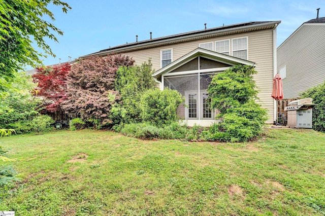 back of property with a yard and a sunroom