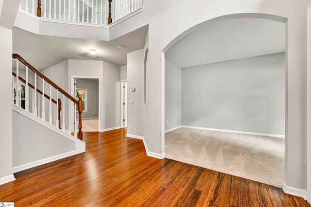 foyer entrance with wood finished floors, baseboards, stairs, and arched walkways