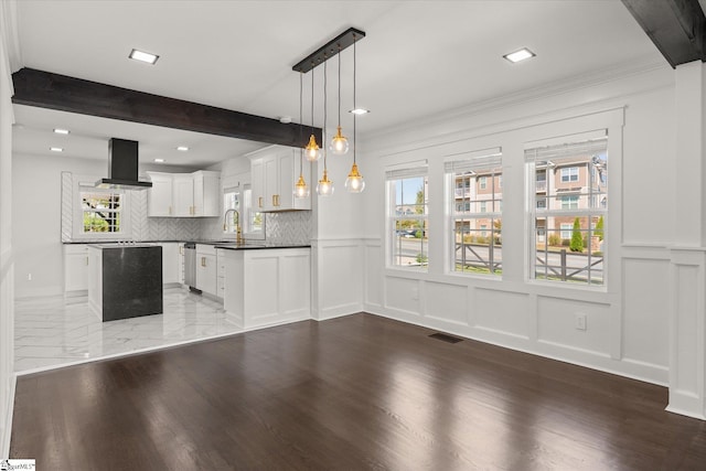 interior space with pendant lighting, stainless steel dishwasher, decorative backsplash, a decorative wall, and range hood