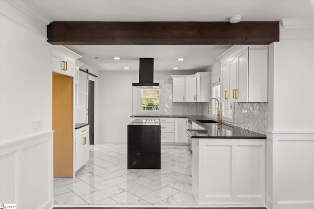 kitchen with beamed ceiling, a sink, a barn door, dark countertops, and island range hood