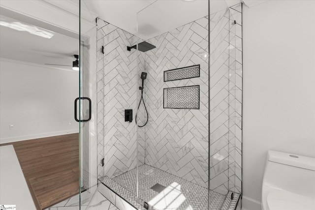 bathroom featuring a shower stall, ceiling fan, toilet, baseboards, and ornamental molding