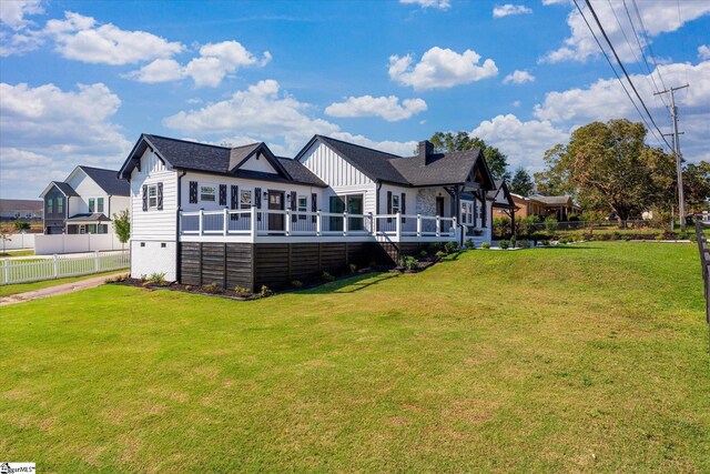 back of property featuring a deck, board and batten siding, a yard, fence, and concrete driveway