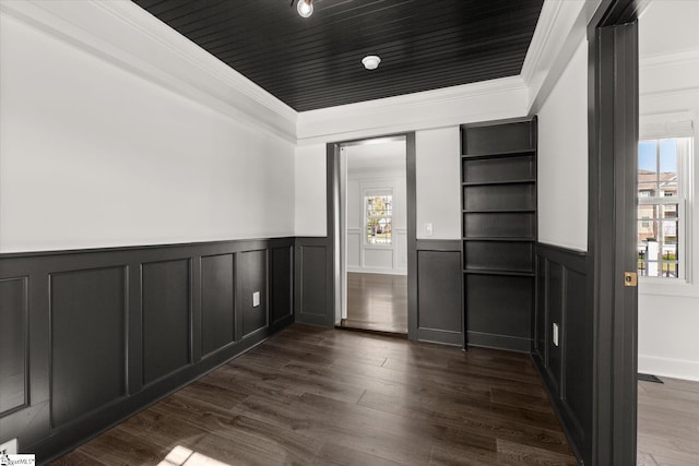 interior space featuring ornamental molding, dark wood-style floors, and a decorative wall