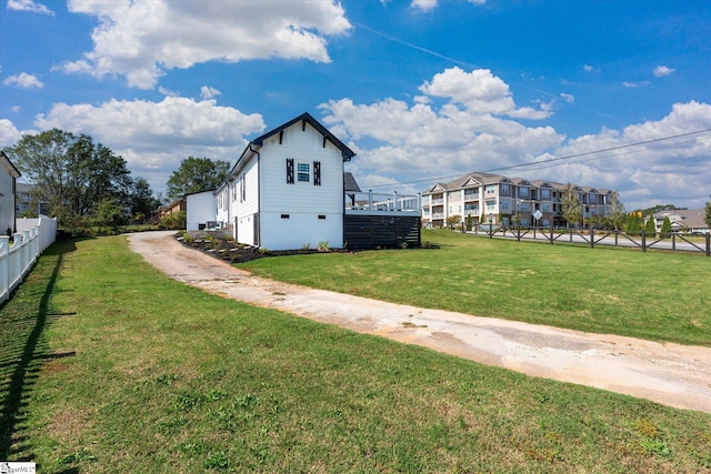 view of side of property featuring fence, driveway, and a lawn
