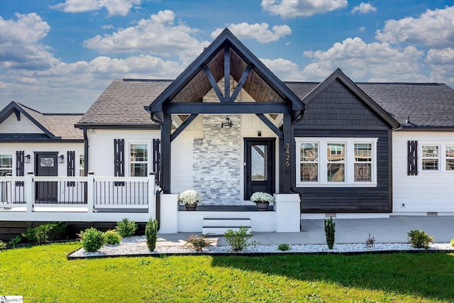 view of front of house featuring a porch, a front yard, a wooden deck, and a shingled roof