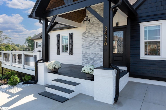 doorway to property with a porch and stone siding