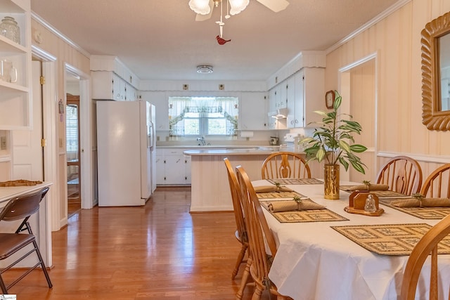 dining space featuring ornamental molding, a ceiling fan, and light wood-style flooring