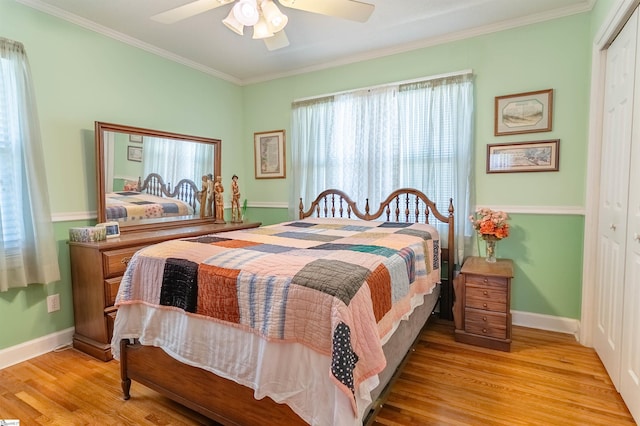 bedroom featuring crown molding, baseboards, wood finished floors, and a closet