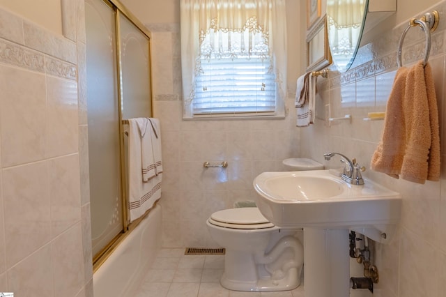 full bath featuring combined bath / shower with glass door, tile patterned floors, toilet, and tile walls