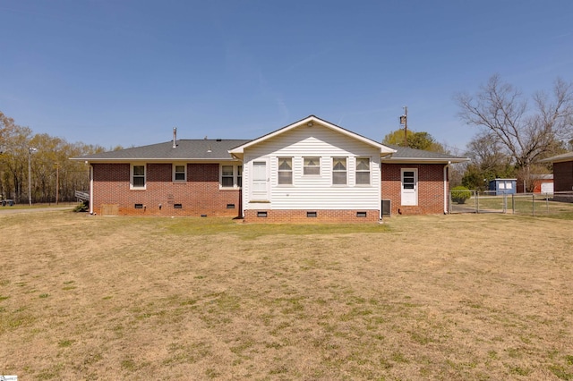 back of property with fence, a yard, brick siding, and crawl space