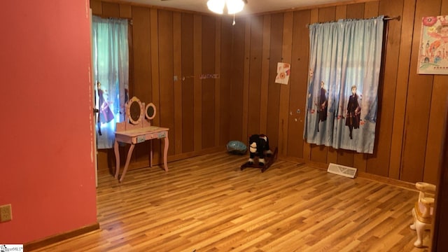 spare room with wooden walls, wood finished floors, and visible vents