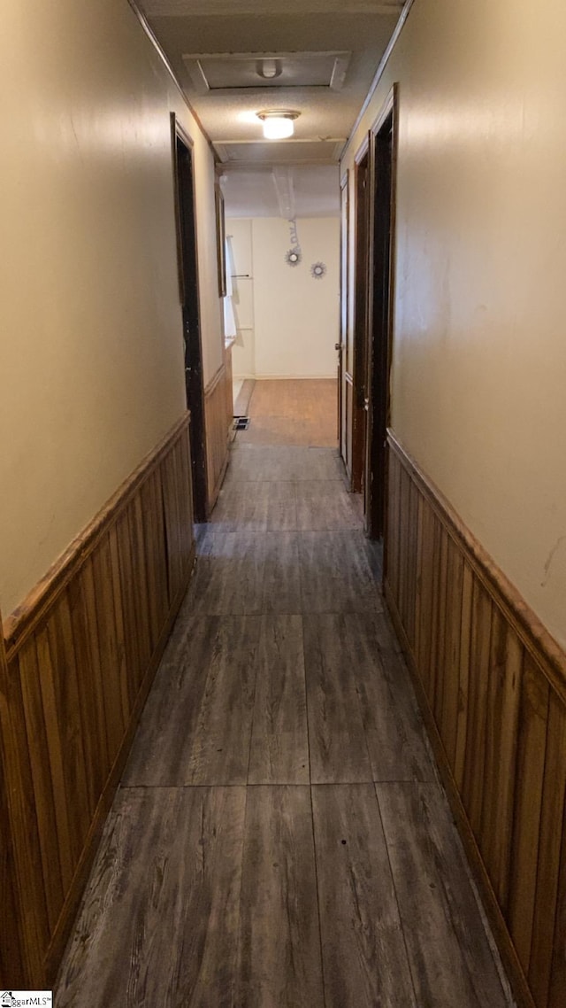 hall featuring wood walls, attic access, a wainscoted wall, and dark wood-type flooring