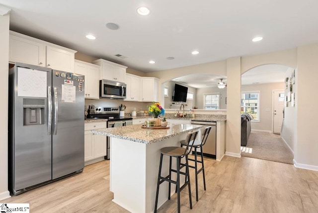 149 Bruinen Dr, Fountain Inn, SC 29644 - kitchen with a kitchen bar, light wood-type flooring, a kitchen island, arched walkways, and appliances with stainless steel finishes