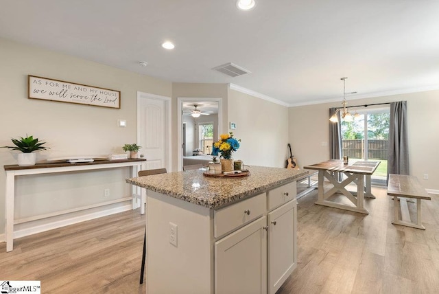 149 Bruinen Dr, Fountain Inn, SC 29644 - kitchen with recessed lighting, light stone counters, light wood-type flooring, a center island, and crown molding