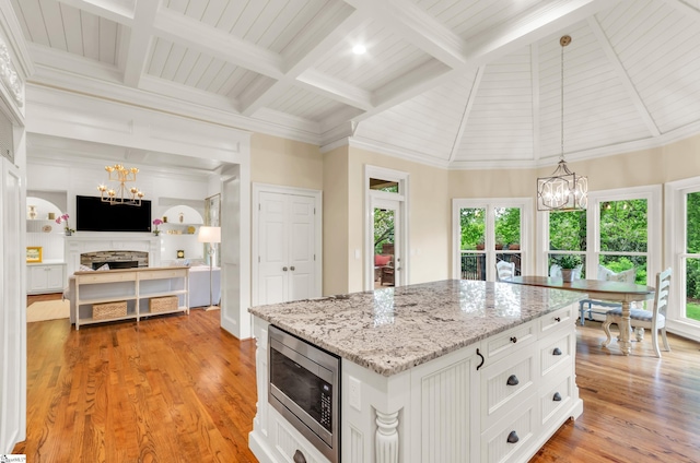 kitchen with a fireplace, plenty of natural light, stainless steel microwave, and a chandelier
