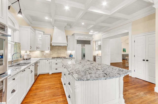 kitchen with a sink, white cabinets, light wood-style floors, and a kitchen island