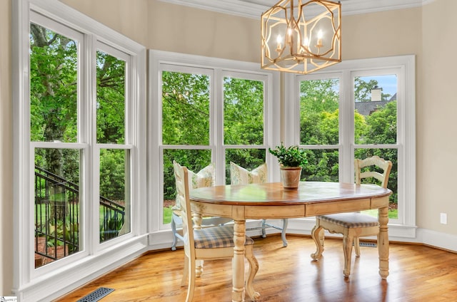 sunroom / solarium featuring visible vents, crown molding, wood finished floors, baseboards, and a notable chandelier