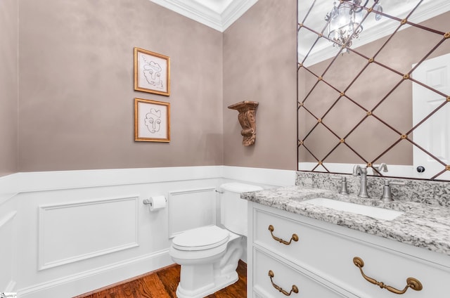 half bathroom with crown molding, toilet, wood finished floors, and vanity
