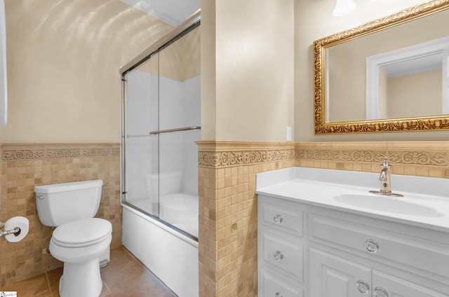 full bathroom featuring toilet, tile walls, and wainscoting
