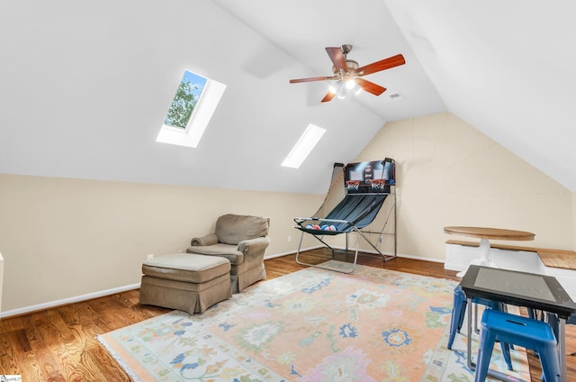 sitting room featuring baseboards, a ceiling fan, lofted ceiling with skylight, and wood finished floors