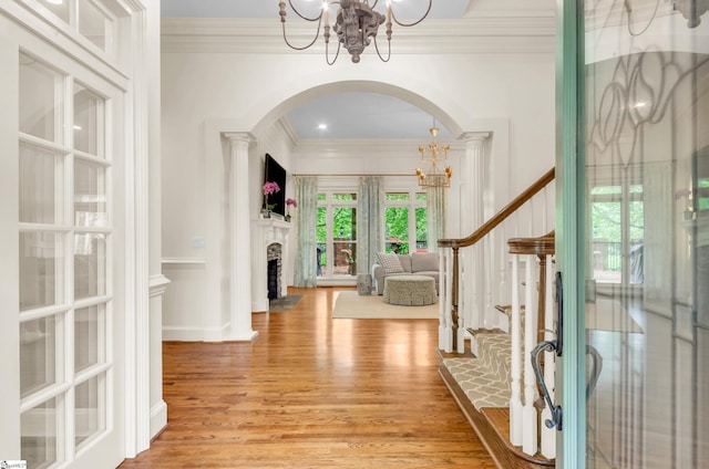 entryway featuring crown molding, a notable chandelier, stairs, and light wood finished floors