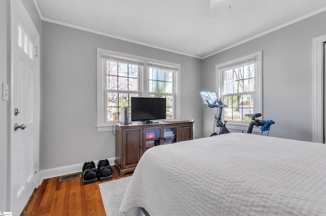 bedroom featuring crown molding, baseboards, visible vents, and wood finished floors