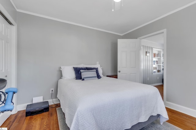 bedroom featuring a ceiling fan, baseboards, wood finished floors, ornamental molding, and a closet