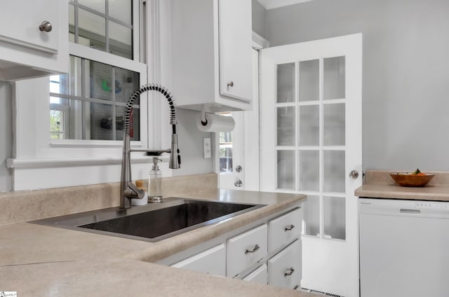 kitchen featuring white cabinets, white dishwasher, a sink, light countertops, and glass insert cabinets