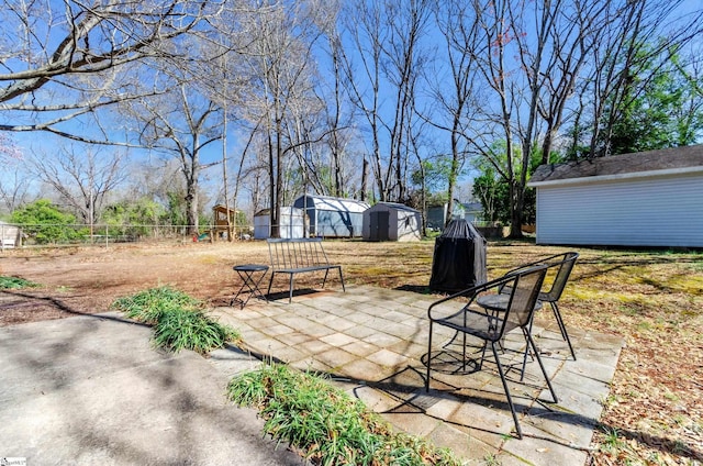 view of patio / terrace with an outdoor structure, a shed, and fence