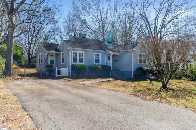 ranch-style house with aphalt driveway, fence, and a chimney