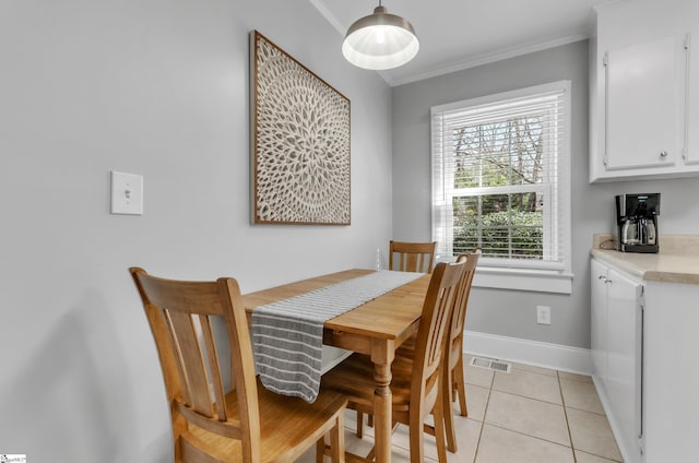 dining space featuring crown molding, baseboards, visible vents, and light tile patterned floors