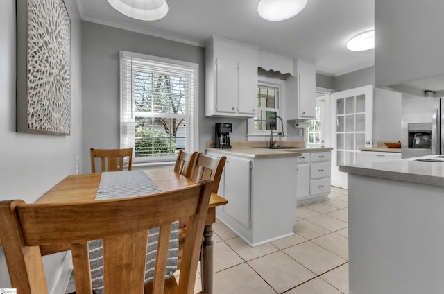 kitchen featuring white cabinetry, a sink, stainless steel fridge, and light tile patterned floors