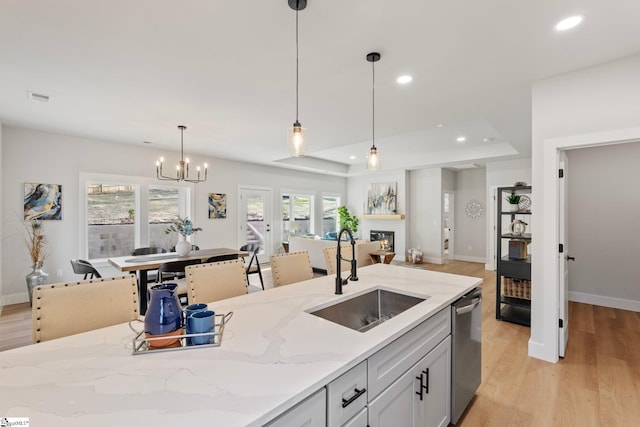 kitchen featuring stainless steel dishwasher, visible vents, open floor plan, a raised ceiling, and a sink