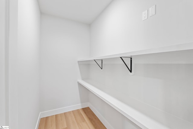 walk in closet with light wood-style floors