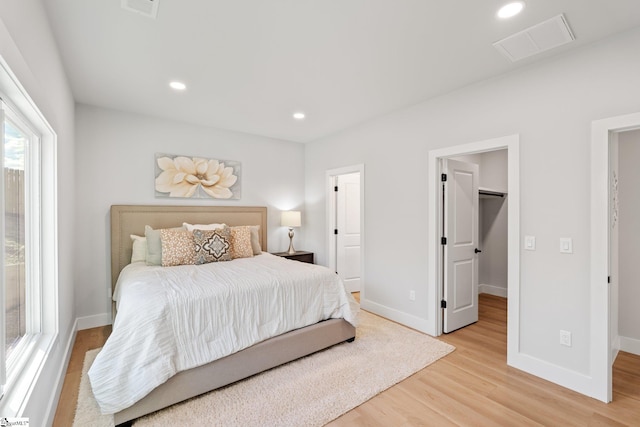 bedroom featuring baseboards, visible vents, a spacious closet, and light wood-type flooring
