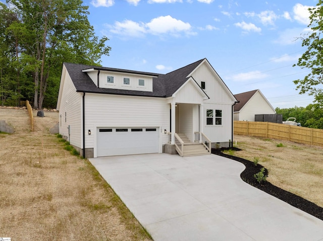 modern farmhouse style home featuring concrete driveway, fence, roof with shingles, and a garage