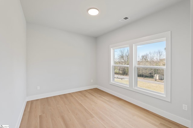 spare room featuring baseboards, light wood finished floors, and visible vents