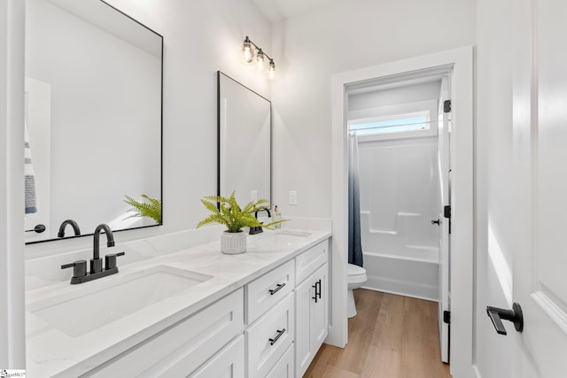 bathroom with double vanity, a sink, wood finished floors, and toilet