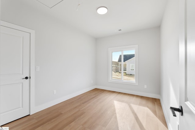 spare room featuring baseboards, light wood-style flooring, and visible vents