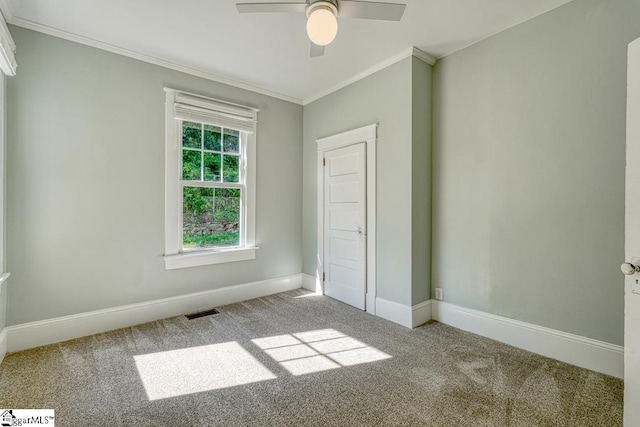 unfurnished bedroom with carpet floors, ornamental molding, visible vents, baseboards, and ceiling fan